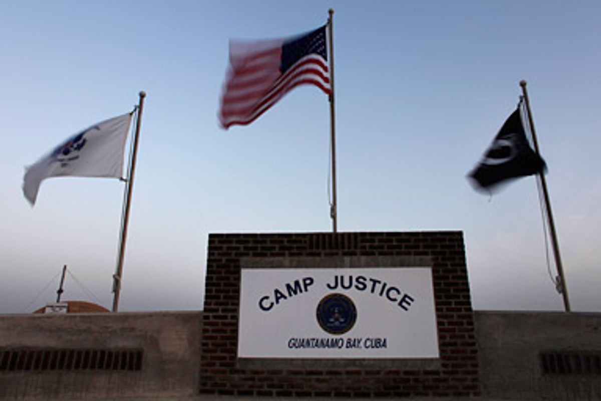 Flags wave above the sign posted at the entrance to Camp Justice, the site of the U.S. war crimes tribunal compound, at Guantanamo Bay U.S. Naval Base in Cuba May 31, 2009. A session of the Guantanamo war crimes court began Sunday for Canadian Omar Khadr who is charged with killing an American soldier.