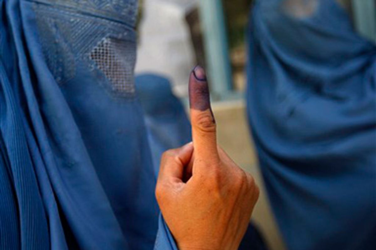 An Afghan woman voter shows her finger to a friend after casting her ballot at a polling station in a school in Kabul, Thursday, Aug. 20, 2009.