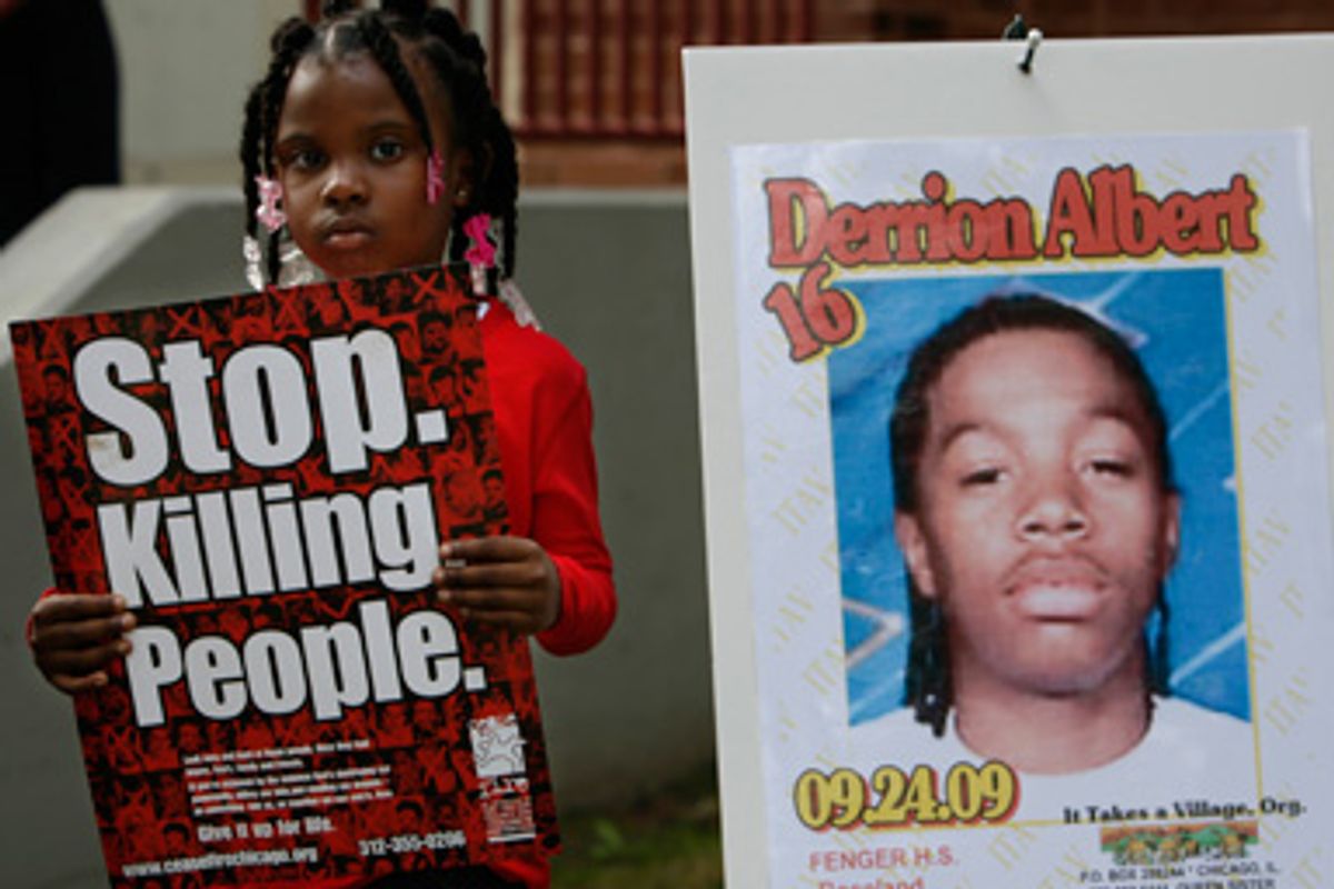 Nadashia Thomas, 6, a cousin of Derrion Albert, holds a sign beside a poster of Derrion Albert at Fenger High School in Chicago, Sept. 28, 2009.      