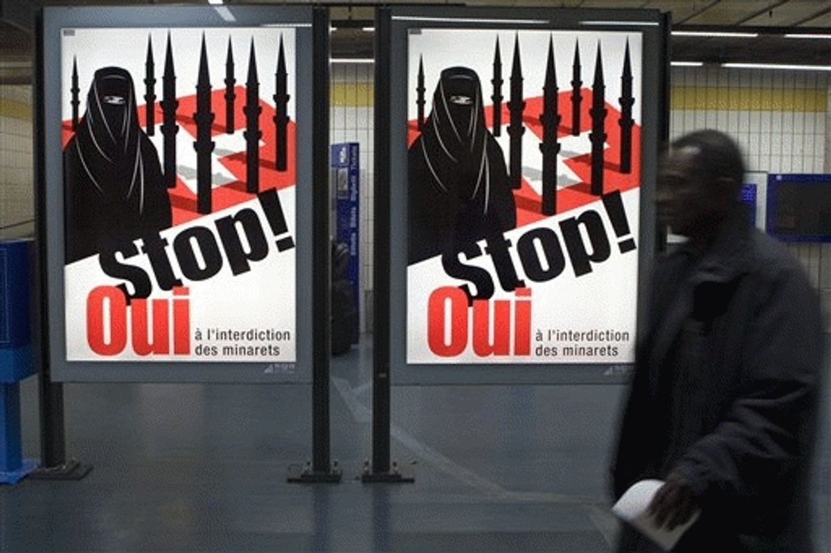 FILE - A man passes by a poster of the right-wing Swiss People's Party which shows a woman wearing a burqa against a background of a Swiss flag upon which several minarets resemble missiles at the central station in Geneva, Switzerland.