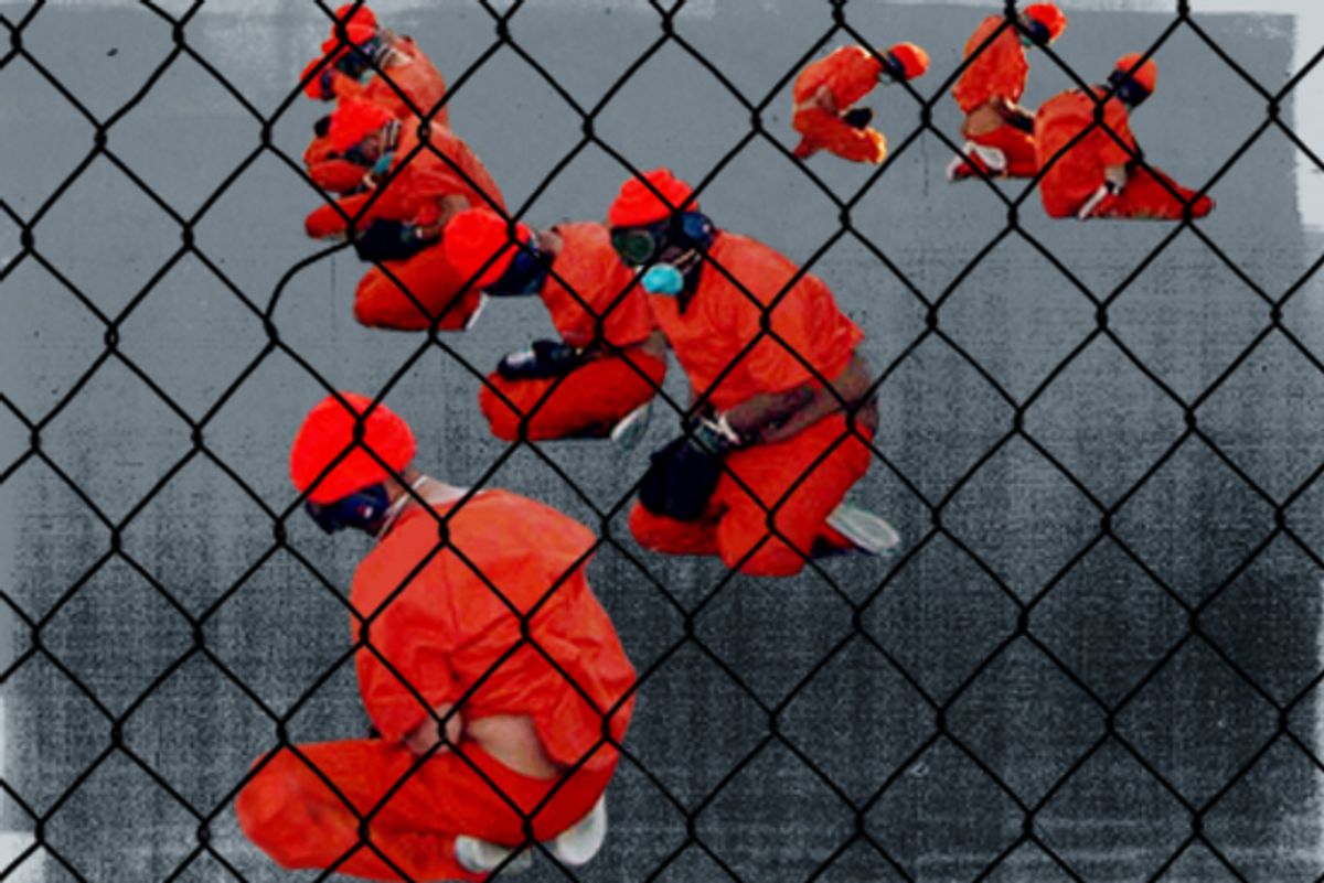 Detainees in orange jumpsuits sit in a holding area in Camp X-Ray at Naval Base Guantanamo Bay, Cuba in 2002.