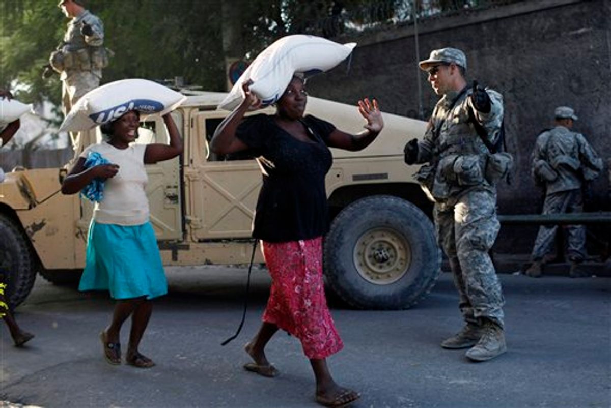 Women carry sacks containing rice during a food distribution watched by U.S. soldiers in Port-au-Prince, Sunday, Jan 31,  2010. Relief workers prepared for a woman-only food distribution system in Haiti's capital, launching a new phase of what they hope will be less cutthroat aid distribution to ensure that families and the weak get supplies following Haiti's devastating Jan. 12 earthquake. (AP  Photo/ Rodrigo Abd)    (AP)