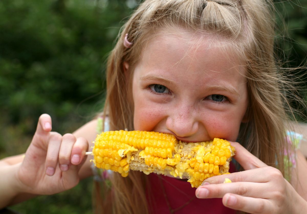 Young funny girl eating a boiled corn 