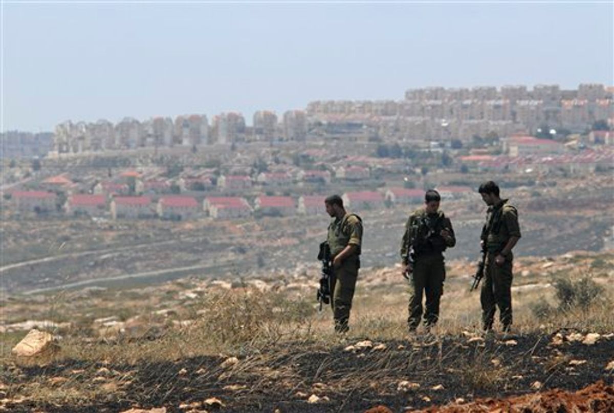 Israeli soldiers stand near a burnt field at the Migron unauthorized settlement outpost in the West Bank after it was demolished by Israeli troops Tuesday, April 27, 2010. Israel announced a freeze on new construction in West Bank settlements in November 2009 under pressure from U.S. President Barack Obama, who opposes settlement construction in the West Bank and east Jerusalem _ lands that the Palestinians claim for a future state.(AP Photo/Alessio Romenzi) (AP)