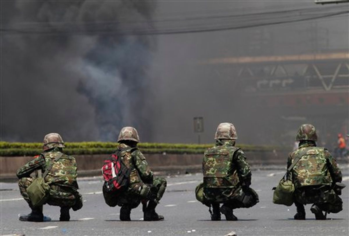 Thai soldiers take position against black smoke as anti-government protesters burned tires in downtown Bangkok, Thailand, Friday, May 14, 2010. Thai troops fired bullets and tear gas at anti-government protesters rioting near the U.S. and Japanese embassies Friday as an army push to clear the streets sparked deadly clashes and turned central Bangkok into a virtual war zone.(AP Photo/Wason Wanichakorn)  (AP)