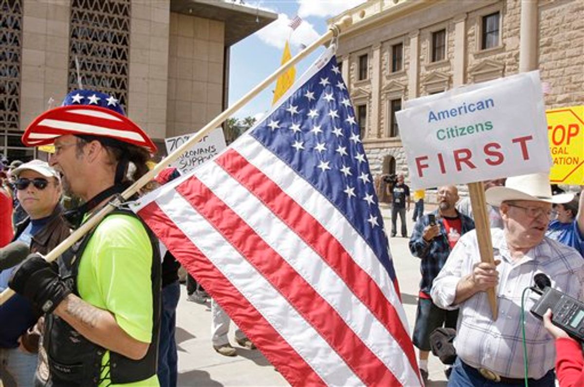 Brian O'Donnell, left, and Robert Kuhn, right, both from Phoenix, stand with dozens rallying in favor of the possible signing of immigration bill SB1070 by Gov. Jan Brewer as hundreds rallied in opposition to it Friday, April 23, 2010, in Phoenix. The sweeping measure would make it a crime under state law to be in the country illegally, and would require local law enforcement to question people about their immigration status if there is reason to suspect they are in the country illegally. (AP Photo/Ross D. Franklin) (AP)