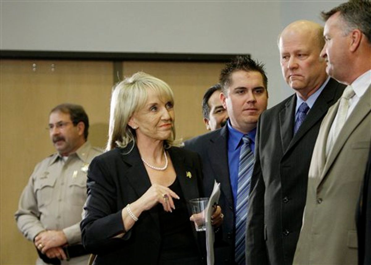 Arizona Gov. Jan Brewer walks past law enforcement members after she signed immigration bill SB1070 into law Friday, April 23, 2010, in Phoenix. The sweeping measure would make it a crime under state law to be in the country illegally, and would require local law enforcement to question people about their immigration status if there is reason to suspect they are in the country illegally. (AP Photo/Ross D. Franklin)     (AP)