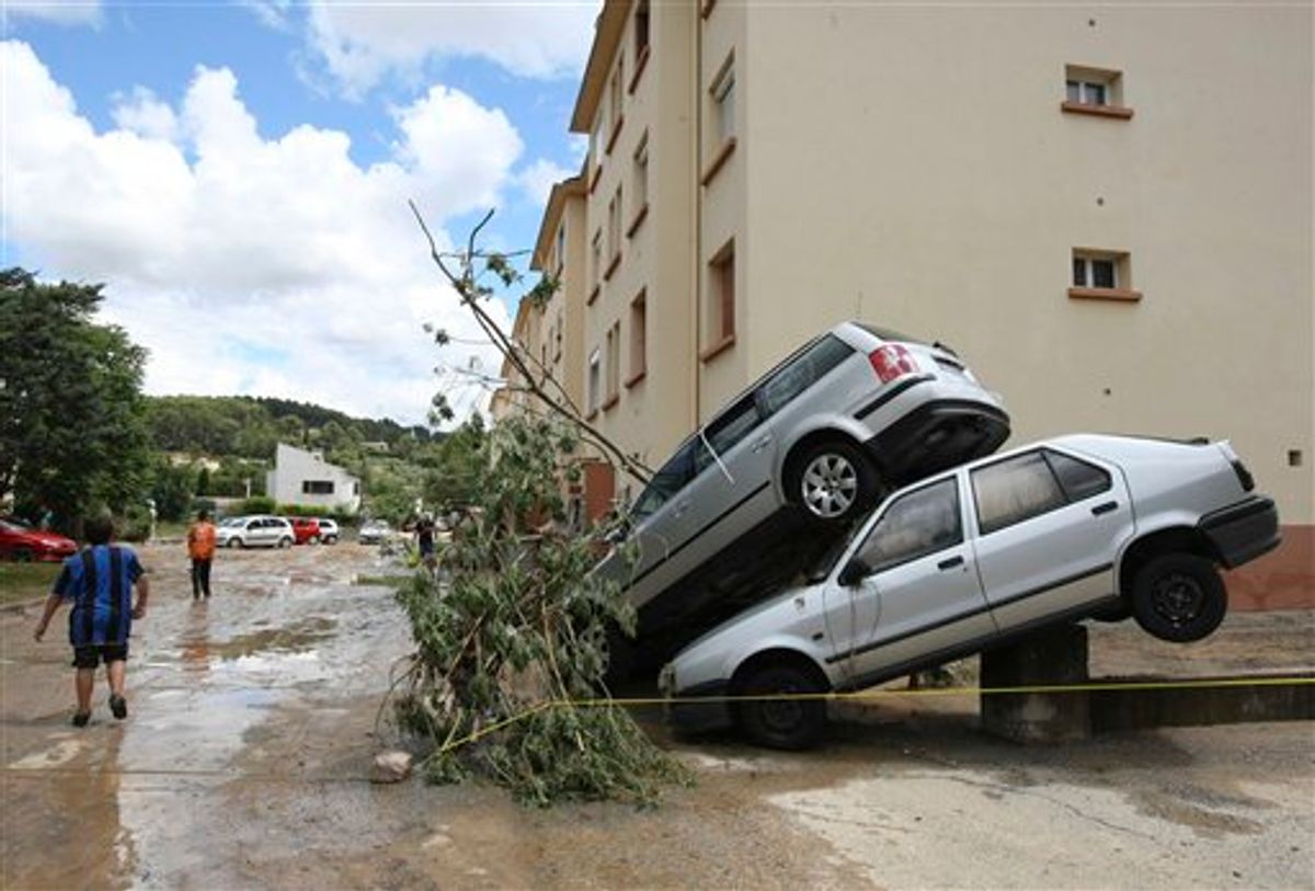 Residents walk past piled cars, in Trans en Provence, southern France, Wednesday, June 16, 2010 after floods. Regional authorities in southeastern France say more than a dozen people have been killed and many are missing in the aftermath of flash floods that followed powerful rainstorms. Unusually heavy rains recently in the Var region have transformed streets into muddy rivers that swept up trees, cars and other objects. (AP Photo/Claude Paris) (AP)