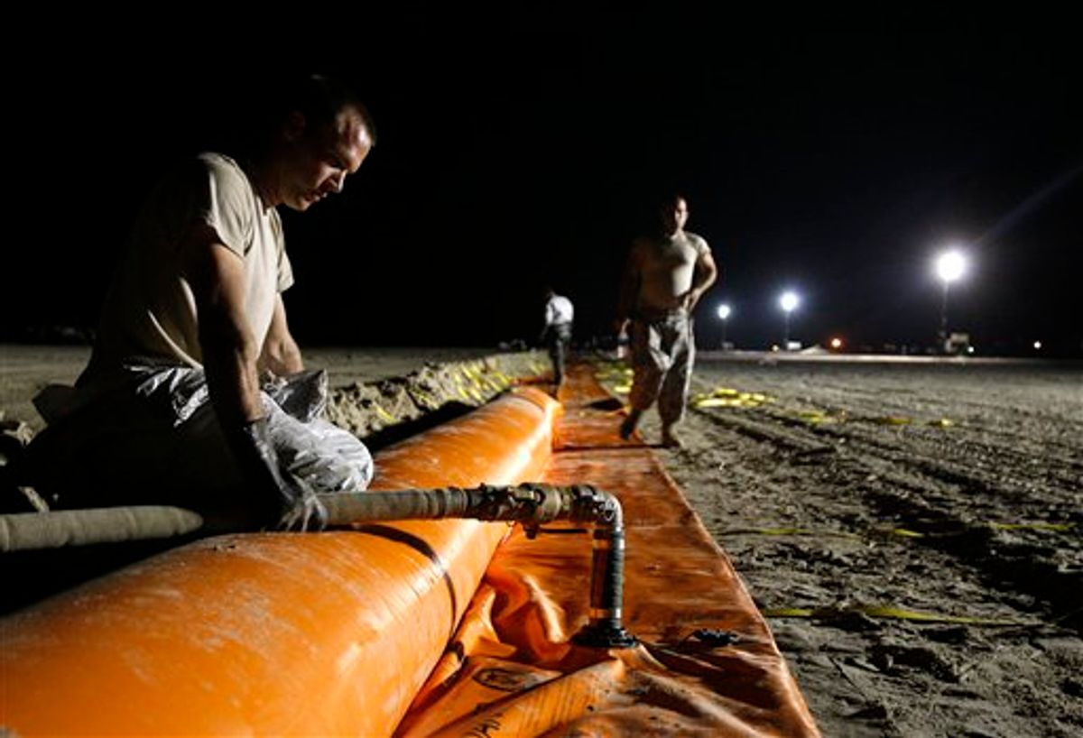 Louisiana National Guard Sgt. Chad Birch, left, fills up a tiger dam with water under floodlights on a beach in Grand Isle, La., Tuesday, June 1, 2010. The National Guard is working around the clock to complete the dam, which is designed to protect the island's entire shoreline along the Gulf of Mexico from oil from last month's Deepwater Horizon oil rig explosion. (AP Photo/Patrick Semansky) (AP)