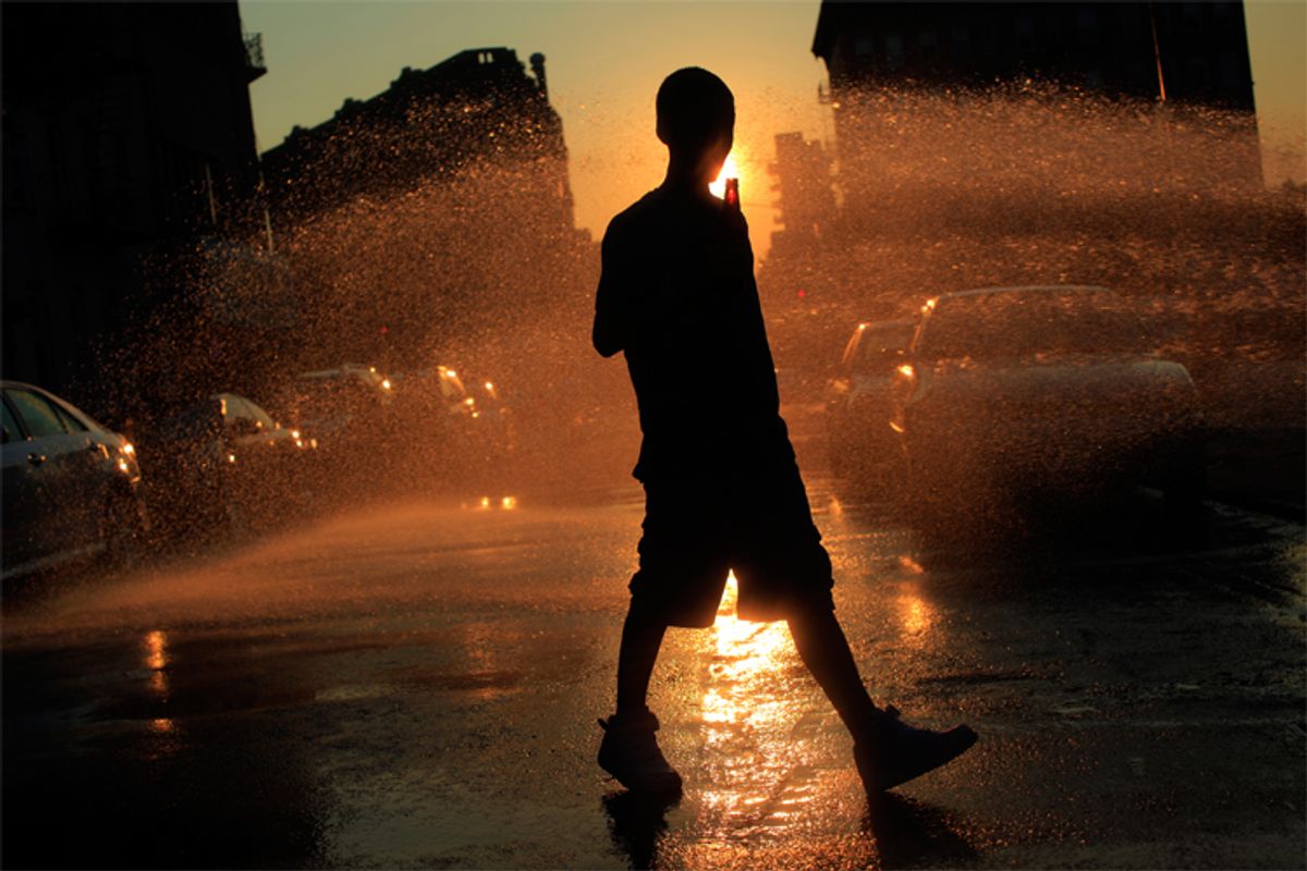 A boy walks near water spraying from an open fire hydrant in Brooklyn, N.Y., on July 5, as temperatures soared toward 100 degrees.