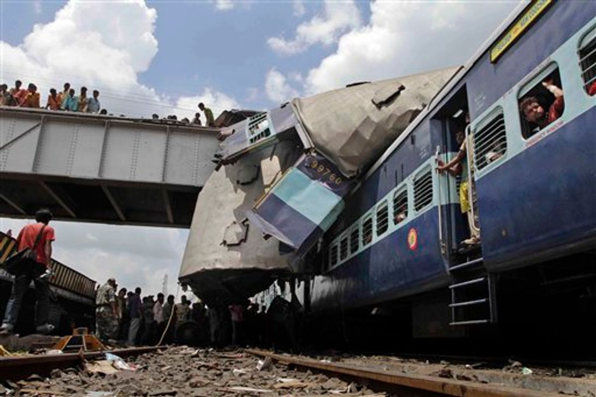 The roof of Uttarbanga Express's passenger car sits on top of Vananchal Express as rescue workers search for survivors at the site of an accident at Sainthia station, about 125 miles (200 kilometers) north of Calcutta, India, Monday, July 19, 2010. The speeding Uttarbanga Express train collided with stationary Uttarbanga Express at the station in eastern India early Monday, mangling the carriages and killing scores of people, railway police said. (AP Photo/Bikas Das) (AP)