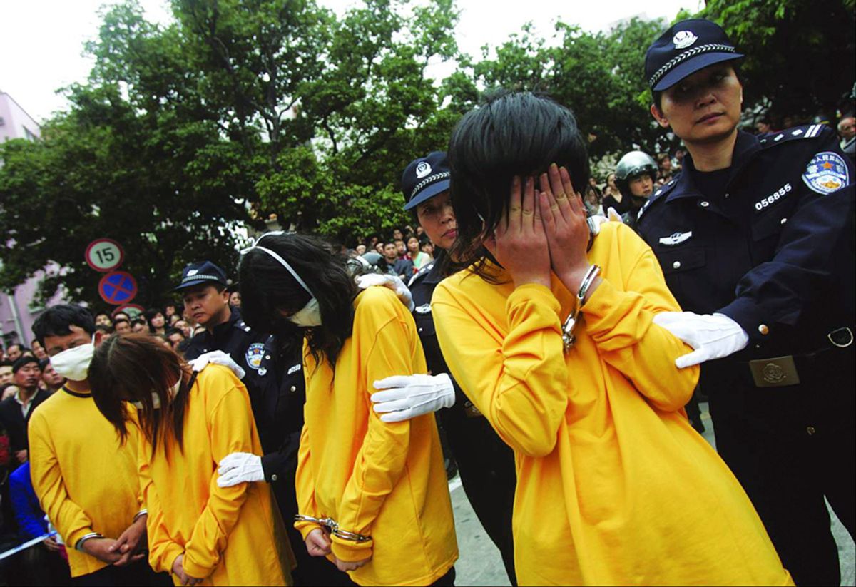 Police officers watch over prostitutes during a public parade in Shenzhen, south China's Guangdong province, November 29, 2006. China has ordered an investigation into a police-organised parade of 100 prostitutes and their clients in the southern city of Shenzhen, Hong Kong newspapers reported on Wednesday. Picture taken November 29, 2006. CHINA OUT REUTERS/China Daily (CHINA)  (Â© China Daily China Daily Inform)