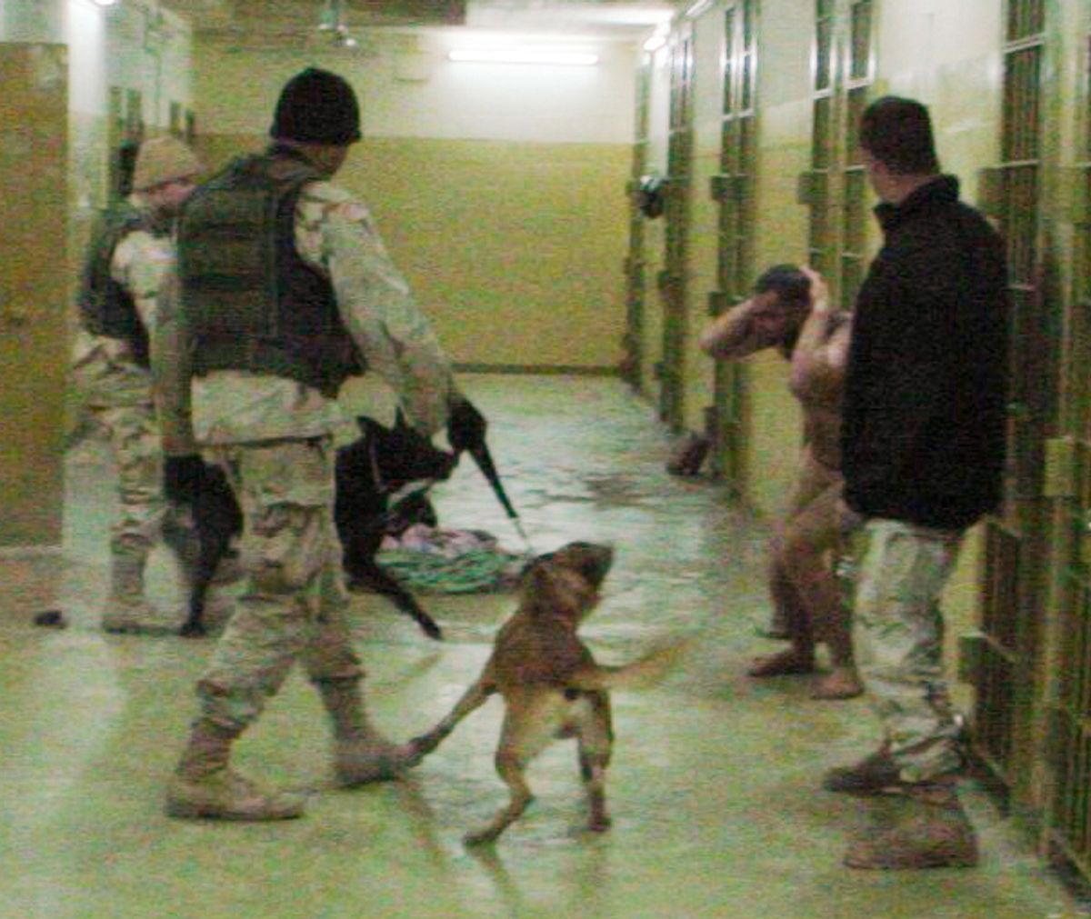 This Dec. 12, 2003 file image shows Sgt. Michael Smith, left, with his black dog Marco, Sgt. Santos Cardona, second right, with his Belgian shepherd Duco, detainee Mohammed Bollendia and Pvt. Ivan L. Frederick II, right, during an incident at the Abu Ghraib prison in Baghdad, Iraq. 