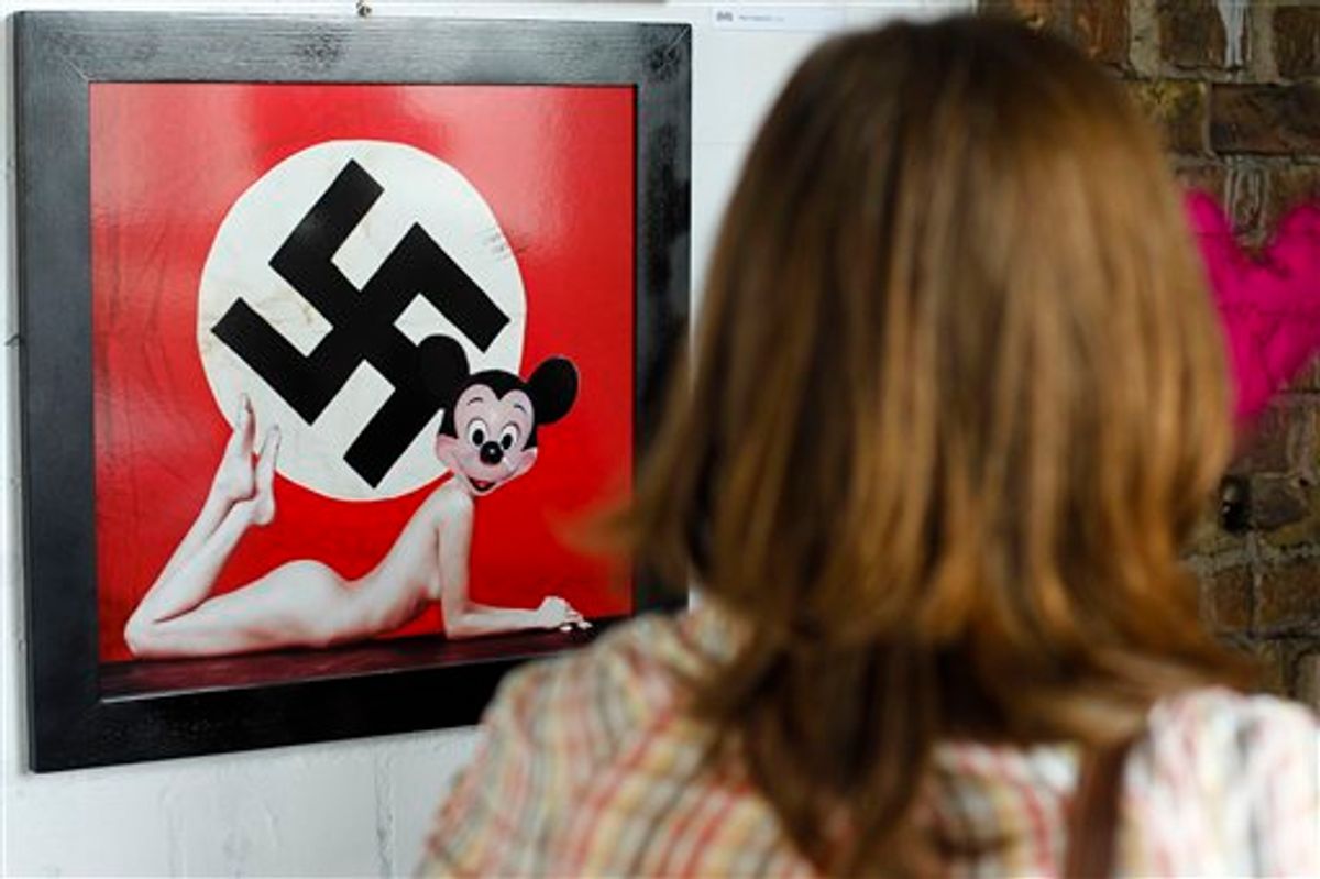 A woman stands in front of a artwork by Italian artist Max Papeschi at the exhibition 'Abnormal Nudes' at the alternative art house Tacheles in Berlin on Tuesday, July 13, 2010. The  art poster hung on a Polish street that blends Mickey Mouse's innocent image with that of a swastika and a nude woman's body is causing a stir in Poland, where memories of suffering inflicted by Nazi Germany remain strong.  The poster, which went up last month in the western city of Poznan just steps from an old synagogue, is an Italian artist's critical take on what he calls the "horrors" of the American lifestyle and is one work in a contemporary art exhibition that is to open in the fall. (AP Photo/Markus Schreiber)    (AP)