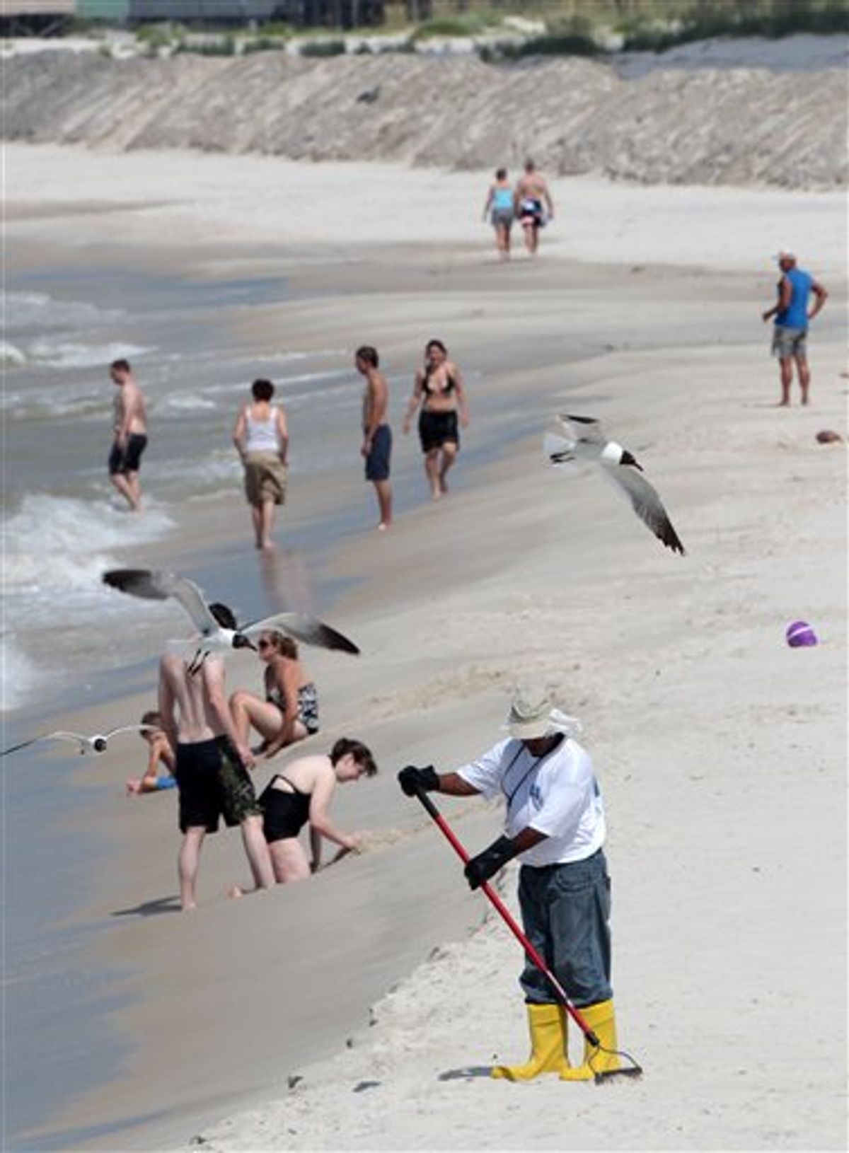 An oil cleanup worker rakes the sand along the beach in Dauphin Island, Ala., on Sunday, July 4, 2010. Workers nearly outnumbered tourists on the beach. Oil from the Deepwater Horizon disaster continues to wash ashore along the Alabama and Florida coasts. (AP Photo/Dave Martin) (AP)