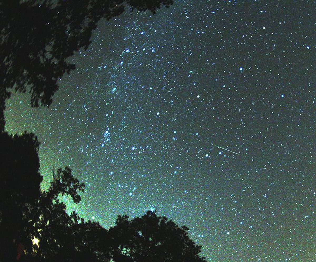 A multicolored Perseid meteor striking the sky just to the right from Milky Way.   