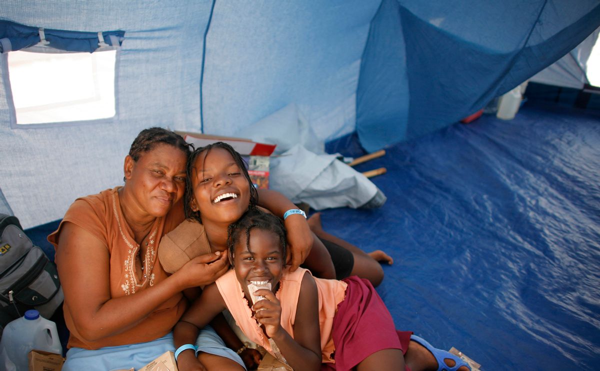 Earthquake survivors pose for a picture in their new tent in Corail, just outside Port-au-Prince, after being relocated there from Petionville Golf Club April 14, 2010. Haiti's government and foreign aid agencies started an operation on Saturday to move thousands of earthquake survivors to a safer refuge to avoid the risk of mudslides and flooding during the rainy season. REUTERS/Eduardo Munoz (HAITI - Tags: DISASTER SOCIETY) (Â© Eduardo Munoz / Reuters)