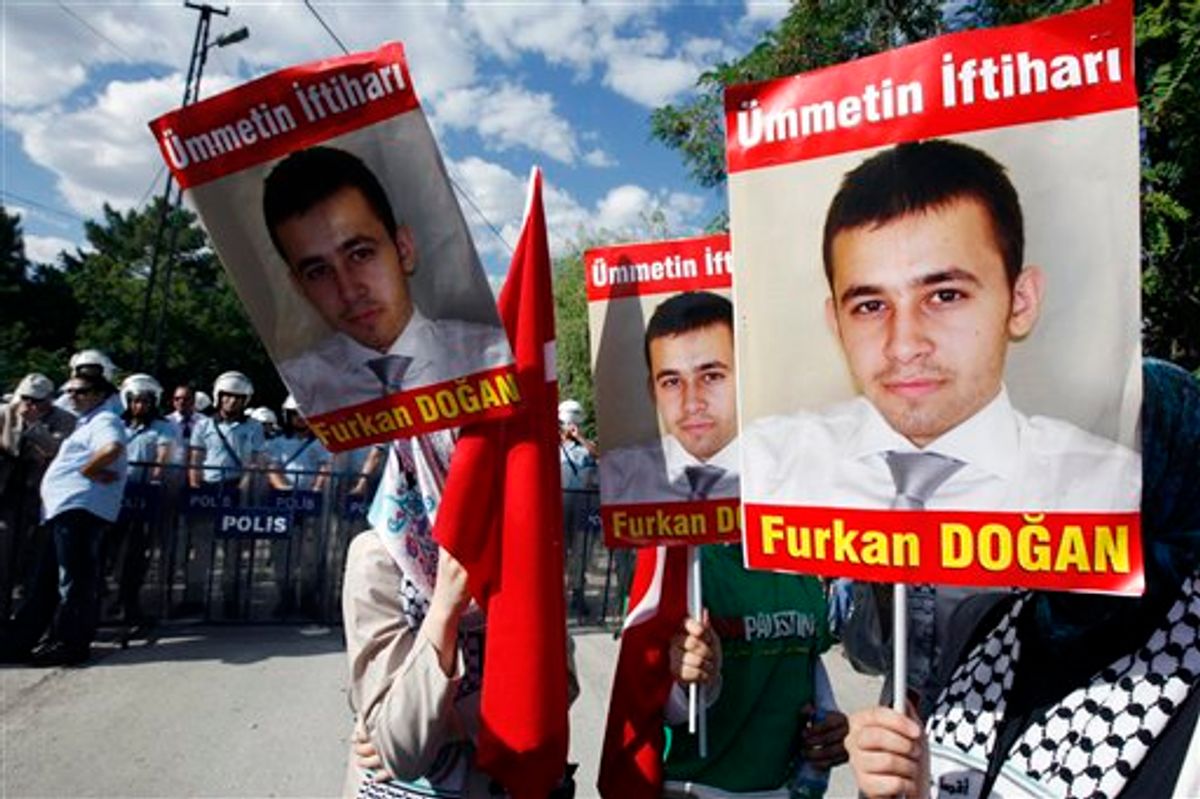 Pro-Palestinian Turks hold posters of Furkan Dogan, the American-Turkish citizen who was born in the U.S. in 1991and one of nine activists killed May 31, 2010, during a pre-dawn military takeover of six aid ships by Israeli forces in the international waters of the Mediterranean Sea, before they clash with  riot police as Israeli volleyball team play against Sebia for CEV Women's European League tournament in Ankara, Turkey, Saturday, July 24, 2010. (AP Photo/Burhan Ozbilici)  (AP)