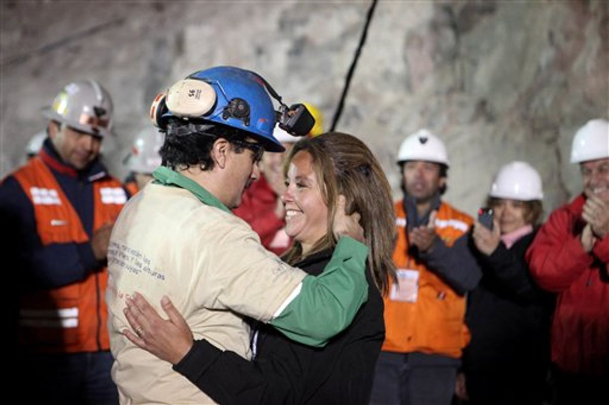 In this photo released by the Chilean government, miner Raul Bustos, left, embraces an unidentified woman after after being rescued from the collapsed San Jose gold and copper mine where he had been trapped with 32 other miners for over two months near Copiapo, Chile, Wednesday Oct. 13, 2010.  (AP Photo/Chilean Government, Hugo Infante) (AP)