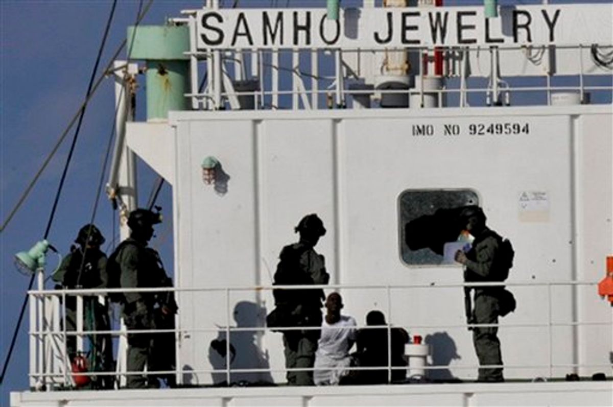 CORRECTS SOURCE - In this photo released by South Korean navy via Yonhap, members of South Korean naval special forces stand guard Somali pirates after detaining them on South Korean cargo ship Samho Jewelry in the Arabian Sea Friday, Jan. 21, 2011. In a daring and rare raid, South Korean special forces stormed the hijacked freighter in the Arabian Sea on Friday, rescuing all 21 crew members and killing eight assailants in a rare and bold raid on Somali pirates, South Korea said. (AP Photo/South Korean navy via Yonhap) KOREA OUT, EDITORIAL USE ONLY (AP)