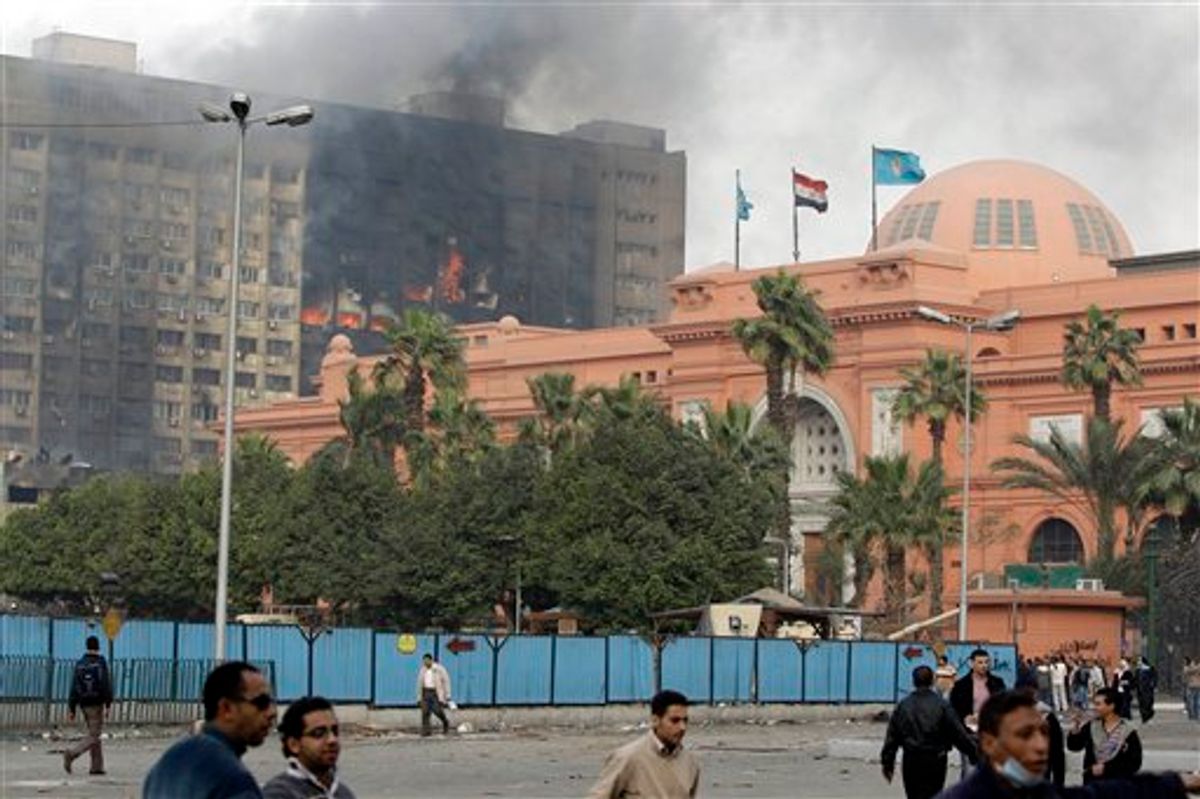 The Egyptian museum is seen intact, right, as smoke billows from the ruling National Democratic party building, torched by anti government protesters overnight, in central Cairo, Egypt, Saturday, Jan. 29, 2011. (AP Photo/Ben Curtis) (AP)