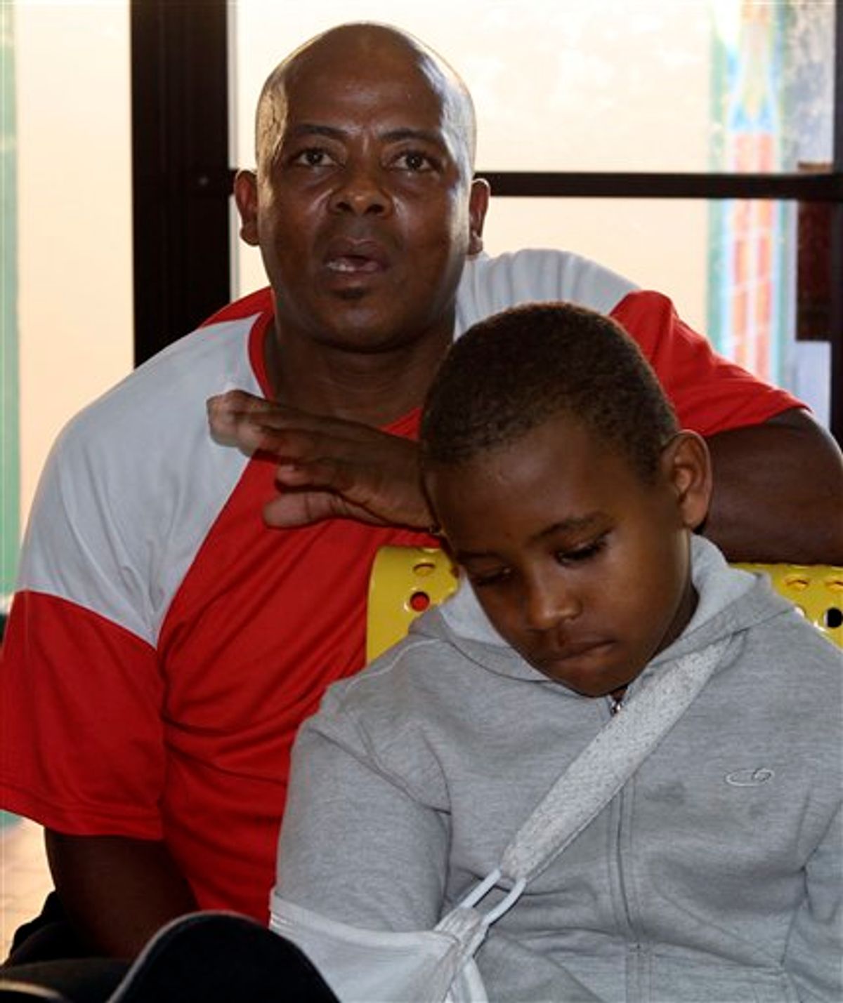 In this photo taken Wednesday, Jan. 5, 2011, earthquake survivors Prevener Julien, left, and his son Belix Julien, eight-years-old, recall the day the earthquake hit Haiti last January 12, 2010, as he talks to a reporter in Miami. (AP Photo/Alan Diaz) (AP)