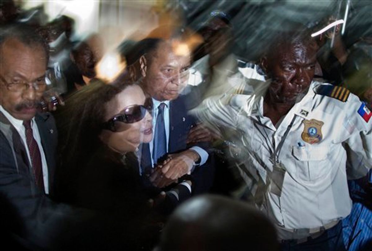** CORRECTS NAME OF WIFE TO VERONIQUE ROY ** Haiti's former dictator Jean-Claude "Baby-Doc" Duvalier, center, and his wife Veronique Roy are helped by a police officer as they are surrounded by reporters upon their arrival to the Toussaint Louverture international airport in Port-au-Prince, Haiti, Sunday Jan. 16, 2011. Duvalier returned to Haiti after nearly 25 years in exile, a surprising and perplexing move that comes as his country struggles with a political crisis and the stalled effort to recover from last year's devastating earthquake. (AP Photo/Ramon Espinosa) (AP)