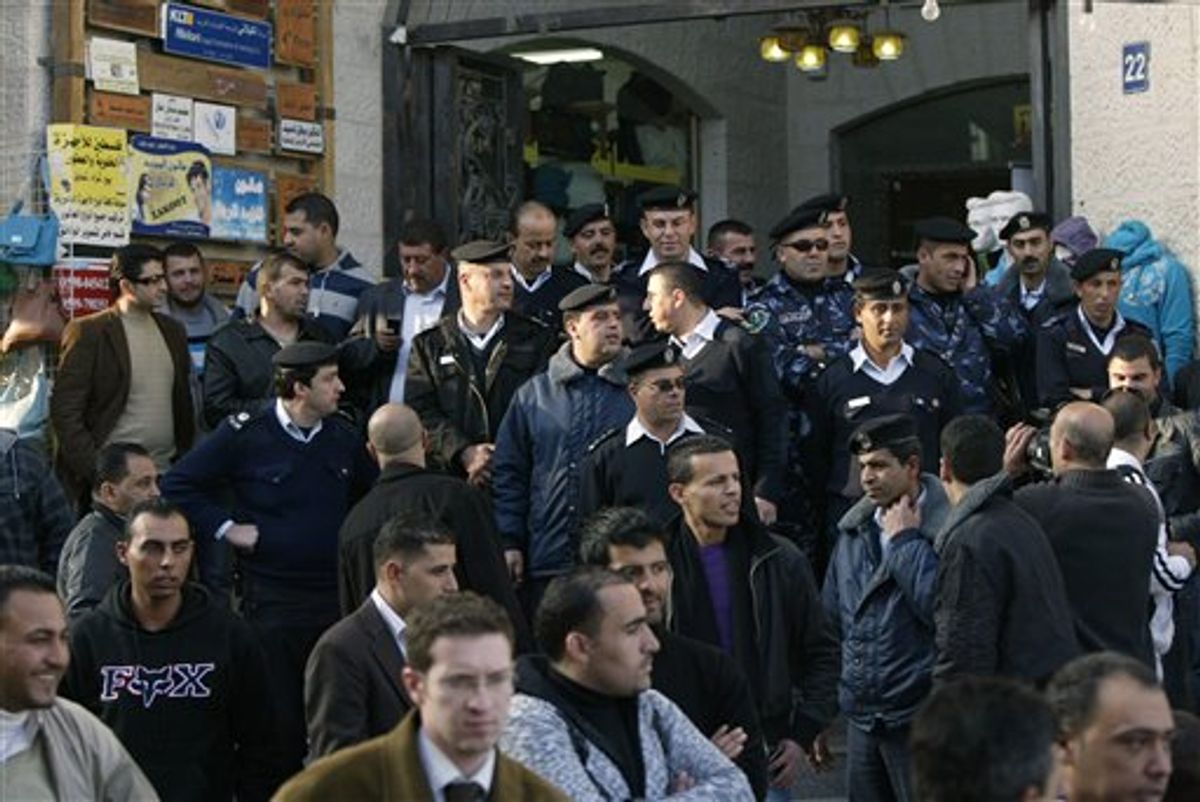 Palestinian police officers block the entrance to the Al-Jazeera TV office, after protesters vandalized it, in the West Bank city of Ramallah, Monday, Jan. 24, 2011. About 250 Palestinian protesters have smashed windows and sprayed graffiti outside the headquarters of the Al-Jazeera TV channel in the West Bank Monday. Al-Jazeera aired late Sunday what it said were leaked documents showing that Palestinian leaders agreed to deep concessions on two of the thorniest issues in negotiations with Israel: Jerusalem and the fate of Palestinian refugees. (AP Photo/Majdi Mohammed) (AP)