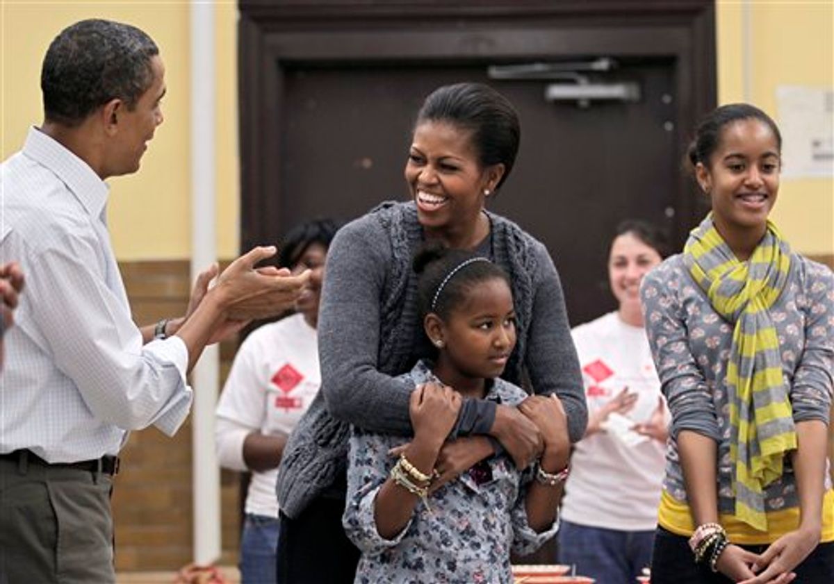 FILE - In this Jan. 17, 2011, file photo first lady Michelle Obama, 47, embracing her daughter Sasha, 9, is surprised by her husband, President Barack Obama, and everyone's singing "Happy Birthday" to her during a community service project at a Washington middle school on the Martin Luther King Jr. holiday. At right is daughter, Malia, 12. Here's Michelle Obama's advice for couples this Valentine's Day: laugh with your partner. She says it's what she and the president do, and it seems to be working. (AP Photo/J. Scott Applewhite)  (AP)