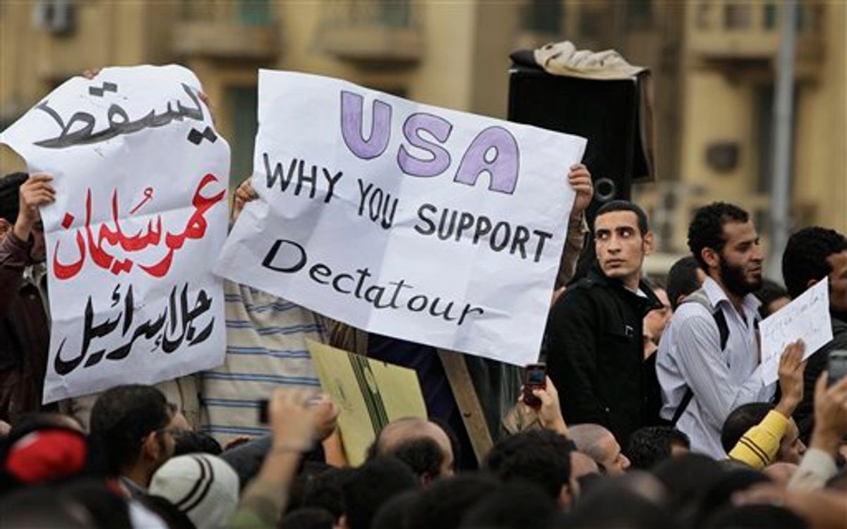 Anti-government protesters carry posters in English reading "USA, why you support dictator", center, referring to Egyptian President Hosni Mubarak and in arabic reading "Down Omar Suleiman, Israel's man", referring to the recently-named Egyptian Vice-President, left, at the demonstration in Tahrir square in downtown Cairo, Egypt, Sunday, Jan. 30, 2011. (AP Photo/Ben Curtis) (AP)