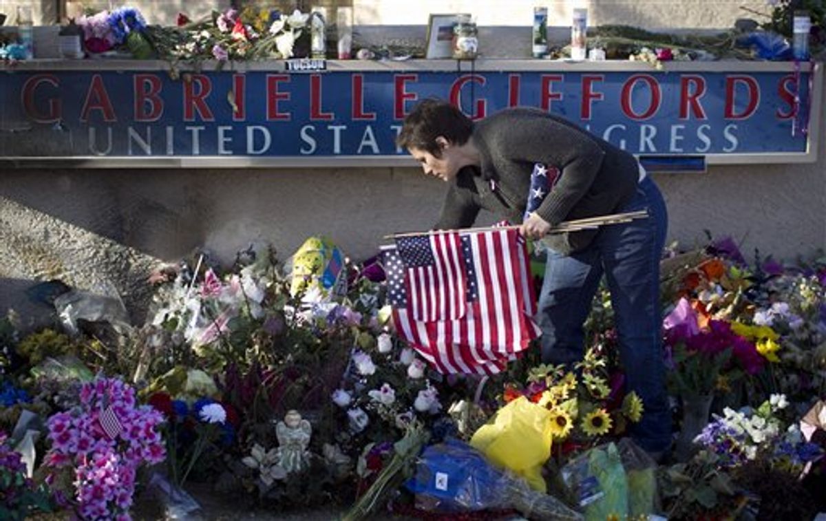 Amanda Sapir picks up flags left at a memorial outside Rep. Gabrielle Giffords Tucson office on Friday, Feb. 4, 2011 in Tucson, Ariz.  Volunteers dismantled a massive tribute Friday outside the Tucson hospital where U.S. Rep. Gabrielle Giffords and other victims of a mass shooting were treated.  The volunteers removed thousands of candles, cards, photos, stuffed animals and flowers that blanketed the 60 foot-by-100 foot lawn in front of University Medical Center, where doctors performed life-saving surgery on the Arizona congresswoman, who is now in a rehabilitation facility in Houston. The items filled up 60 boxes, which will be stored in a locked area at the hospital until a permanent memorial can be built, hospital spokeswoman Darci Slaten said.  (AP Photo/ The Arizona Republic, Pat Shannahan) (AP)