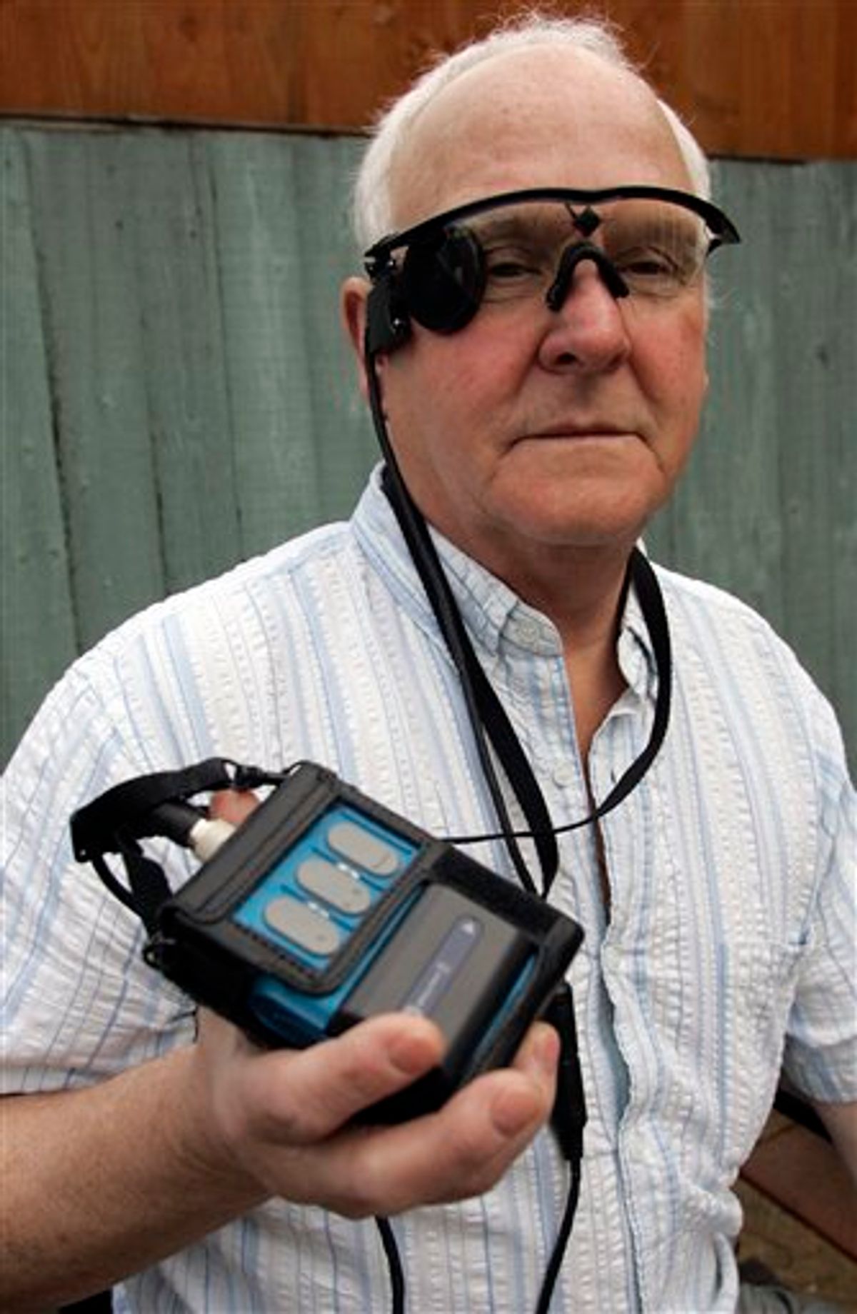 In this photo taken Saturday, Feb. 12, 2011, Eric Selby poses for a photograph with a "sight" camera fitted in a pair of glasses, as well as its associated computer and transmitter, which work in conjunction with an artificial retina implant called the Argus II fitted in his right eye, enabling him to detect light, in Coventry, England. For two decades, Eric Selby, 68, had been completely blind and dependent on a guide dog to get around. But after having an artificial retina put into his right eye, he can detect ordinary things like the curb and pavement when he's walking outside. (AP Photo/Martin Cleaver) (AP)