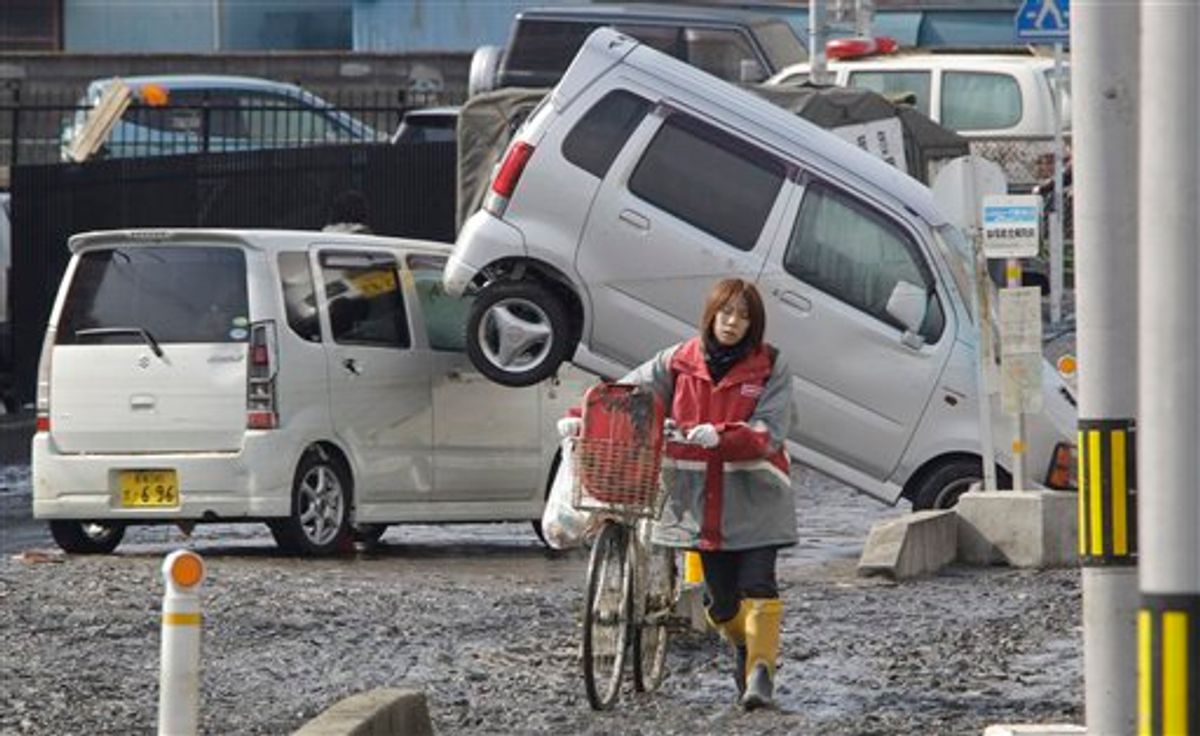 A woman pushes a bicycle on a street following a massive tsunami that's triggered by a catastrophic earthquake in Tagajo near Sendai, northeastern Japan, on Sunday, March 13, 2011. (AP Photo/Koji Sasahara) (AP)