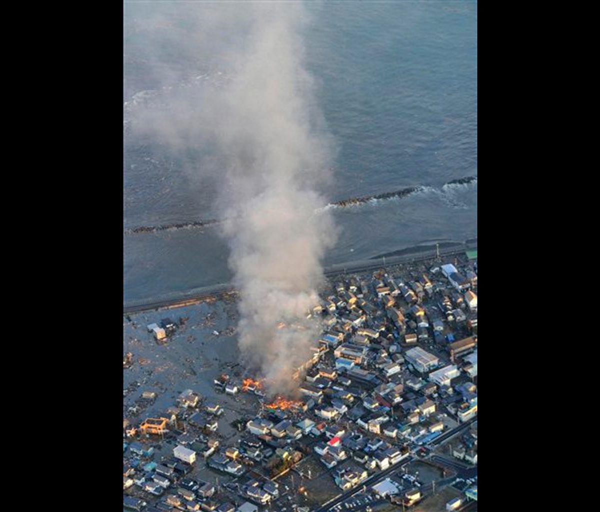 Fire smokes billow from residences as a coastal area is flooded by waters after a tsunami in Iwaki, Fukushima prefecture (state), Japan, Friday, March 11, 2011. (AP/Kyodo News)