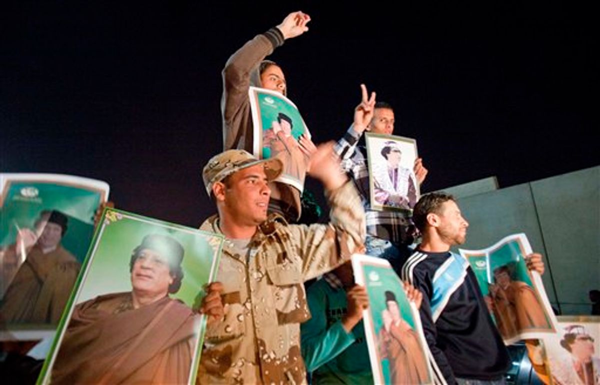 Holding posters of their leader, supporters of Moammar Gadhafi chant slogans following a NATO airstrike in Tripoli, Libya, early Saturday, April 23, 2011. (AP Photo/Darko Bandic) (AP)