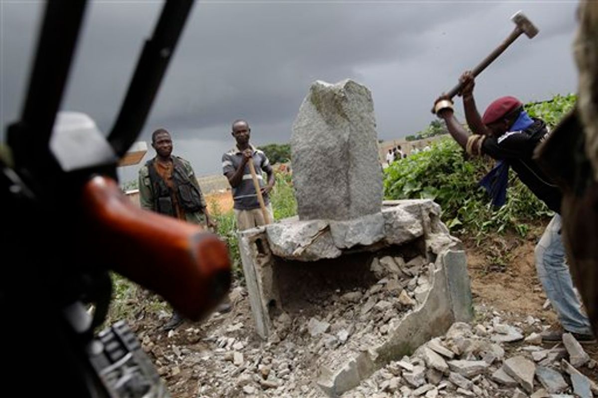 A soldier allied with Alassane Ouattara knocks down a monument believed to mystically provide strength and support to Laurent Gbagbo, in the Youpougon neighborhood of Abidjan, Ivory Coast, Sunday, April 10, 2011. Human Rights Watch, in a report obtained by The Associated Press late Saturday, called on Alassane Ouattara to investigate and prosecute abuses by his forces and those supporting his rival, strongman Laurent Gbagbo.  (AP Photo/Rebecca Blackwell) (AP)
