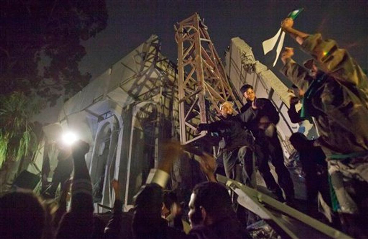 In this photo made on a government organized trip, Moammar Gadhafi supporters climb on the ruins of a damaged building in Tripoli, Libya, early Monday, April 25, 2011. An air strike on Gadhafi's sprawling residential compound early Monday badly damaged two buildings, including a structure where Gadhafi often held meetings, guards at the complex said. (AP Photo/Darko Bandic) (AP)