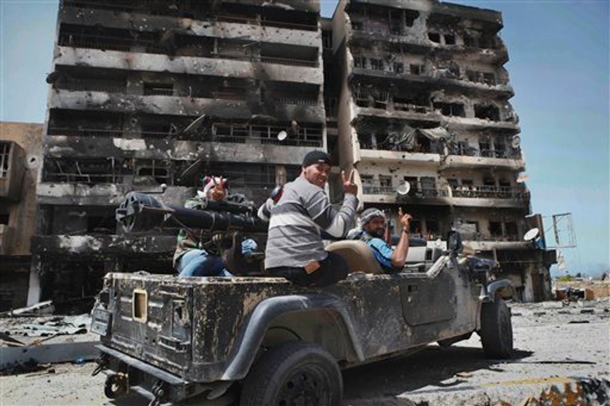 Libyan rebel fighters flash the victory sign as they drive past a heavily-shelled building searching for pro-Gadhafi forces in the besieged city of Misrata, Libya, Saturday, April 23, 2011. Government troops retreated to the outskirts of Misrata under rebel fire Saturday and the opposition claimed victory after officials in Tripoli decided to pull back forces loyal to Moammar Gadhafi following nearly two months of laying siege to the western city. (AP Photo) (AP)