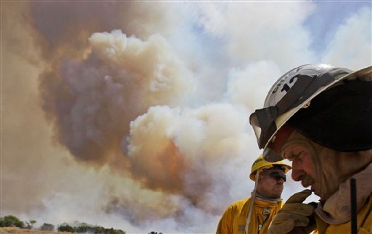 Fire fighters Craig Howard, right and Jason Collard wait for radioed instructions as smoke rises from a nearby wildfire near Possum Kingdom, Texas, Tuesday, April 19, 2011. (AP Photo/LM Otero) (AP)