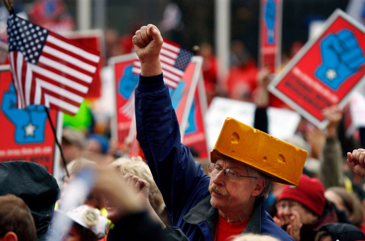 A man wears a cheese-wedge-hat as he pumps his fist in the air outside New Jersey's Statehouse in Trenton, N.J.,  Friday, Feb. 25, 2011, while people wave signs and shout as labor unions and supporters rally in support of Wisconsin workers locked in a battle over collective bargaining rights.   Wisconsin state workers protesting a move by Gov. Scott Walker to severely curtail their collective bargaining rights have found allies in New Jersey. (AP Photo/Mel Evans) (Mel Evans)