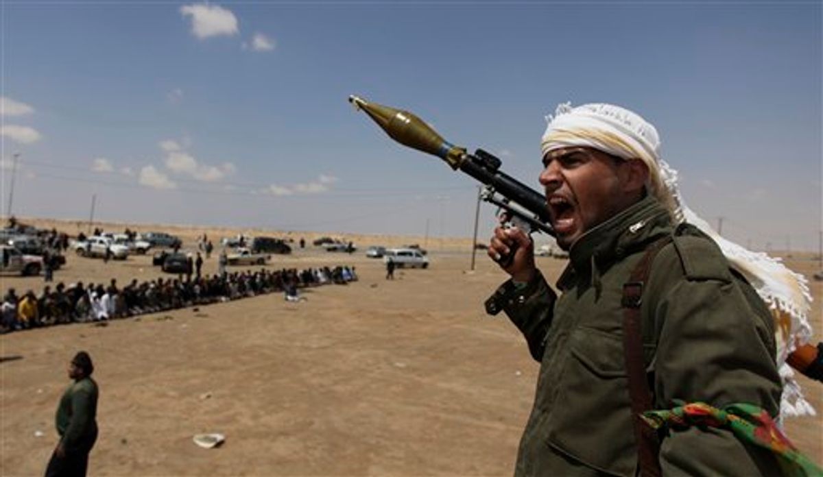 A Libyan rebel fighter, holding a rocket launcher, shouts religious slogans after gun shots were heard as fellow comrades offer prayers in the background in Ajdabia, Libya, Friday, April 8, 2011. Rebel fighters sent scouts Friday toward the contested oil port of Brega to seek clues on whether pro-government forces took advantage of a mistaken NATO airstrike that pounded opposition tanks and sent survivors into retreat. (AP Photo/Altaf Qadri) (AP)