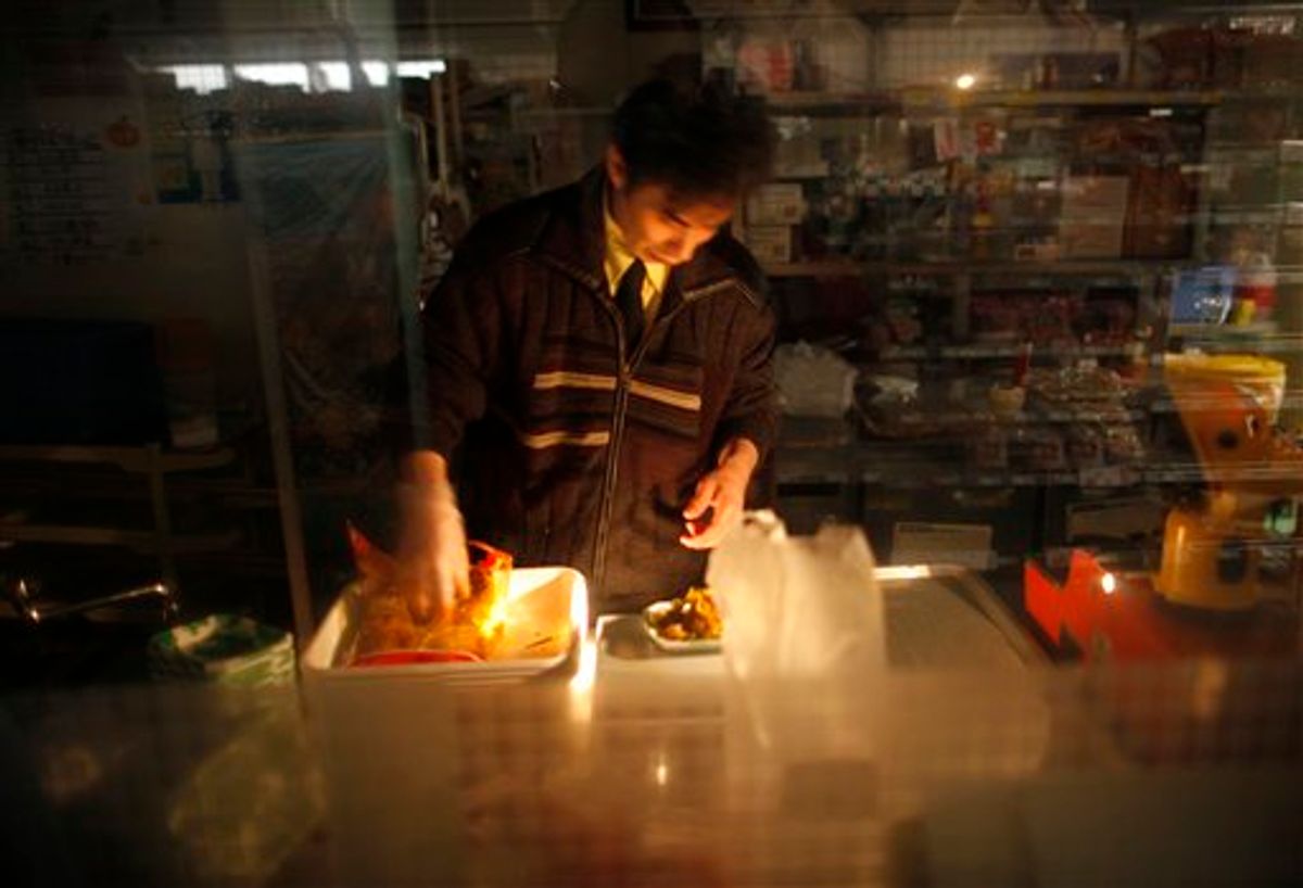 A staff of a supermarket prepares foods at the facilities with no electricity in Ishinomaki, Miyagi Prefecture, northern Japan Friday, April 8, 2011. A big aftershock rocked quake-weary Japan late Thursday, rattling nerves as it knocked out power to the northern part of the country and prompted tsunami warnings that were later canceled.  (AP Photo/Vincent Yu) (AP)