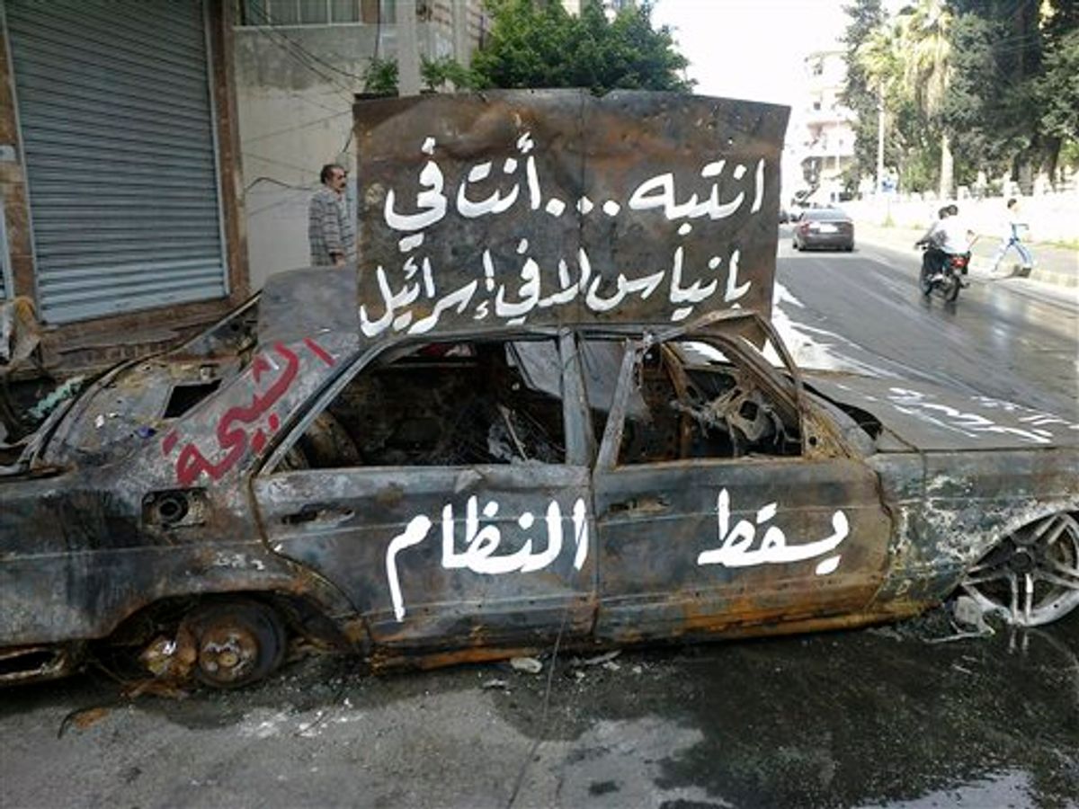 In this citizen journalism image made on a mobile phone and acquired by the AP, and taken Sunday, April 17, 2011, Arabic writing on a burnt car reads:" pay attention, you are in Banias not in Israel. Down with the regime, the "Shabiha" which is a term used in Syria to describe pro-government thugs" in the port city of Banias, Syria. Thousands of people gathered in the central Syrian city of Homs main square Monday following the funeral of six people who were shot dead a day earlier saying they will hold an open-ended sit-in until President Bashar Assad's regime is brought down, witnesses said. (AP Photo) (AP)