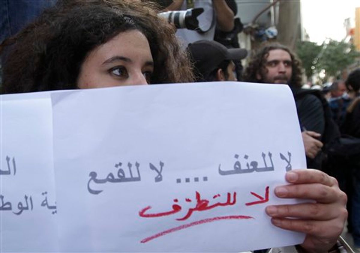 A pro-reform in Syria activist, hold an Arabic placard read:"No to violence, no to oppression and no to fanaticism", as she stands in front of the Syrian embassy, in Beirut, Lebanon, on Tuesday April 12, 2011. Three pro-reform activists stood in front of the Syrian embassy in Beirut where they delivered a statement supporting the people's demands and urging the government to extend its hand to Syrians who want change. Shortly afterward dozens of pro-regime Syrians arrived at the embassy and tried to attack the three men, who were later escorted away under the protection of Lebanese policemen. (AP Photo/Hussein Malla) (AP)