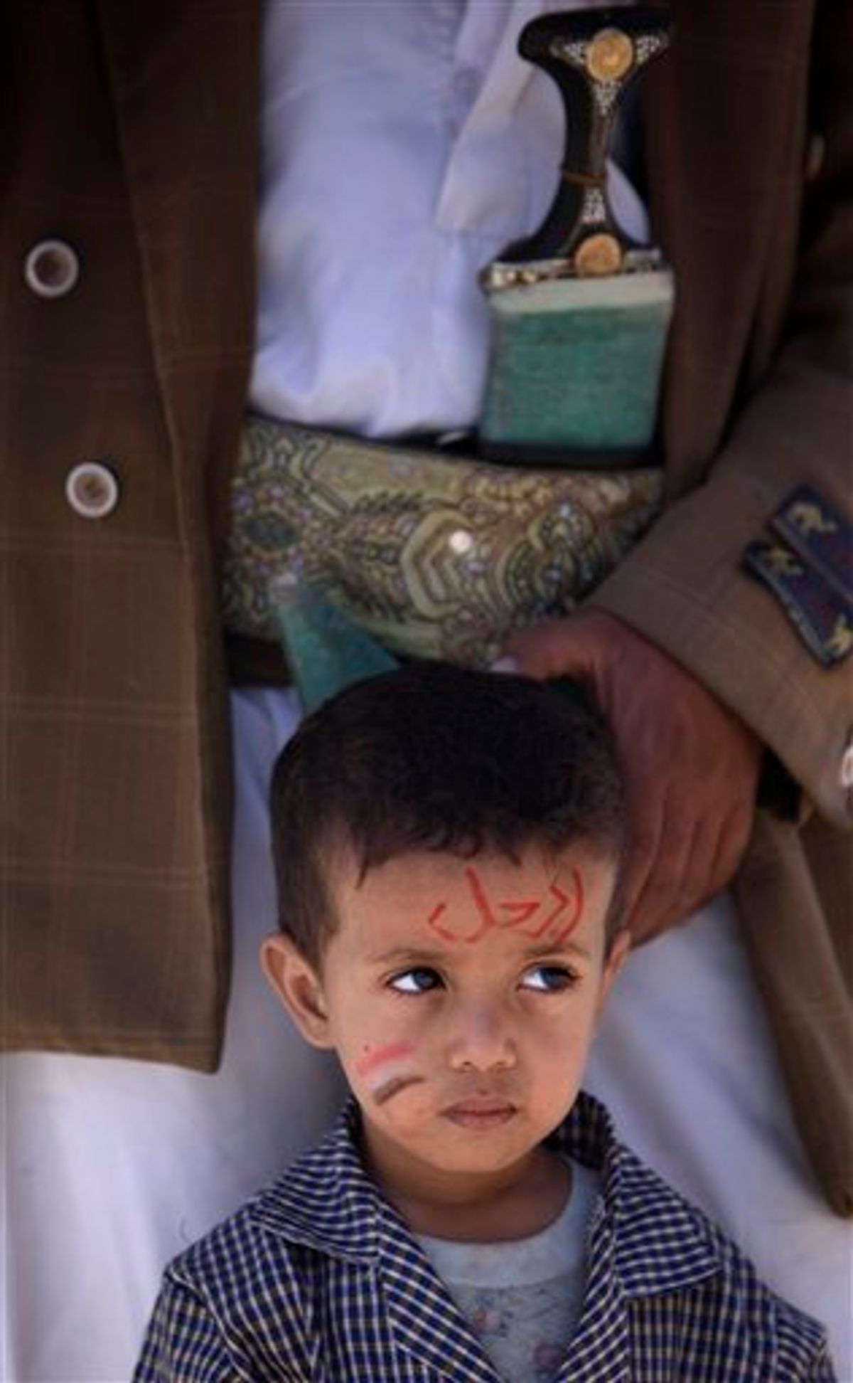 A Yemeni boy with writing on his face in Arabic which reads, "Leave" stands with his father during a demonstration demanding the resignation of Yemeni President Ali Abdullah Saleh in Sanaa, Yemen, Thursday, April 21, 2011. The head of a regional Gulf Arab political group was in Yemen on Thursday to lead a fresh effort to find a way out for the country's embattled president who has faced two months of mass protests demanding his ouster. (AP Photo/Muhammed Muheisen) (AP)