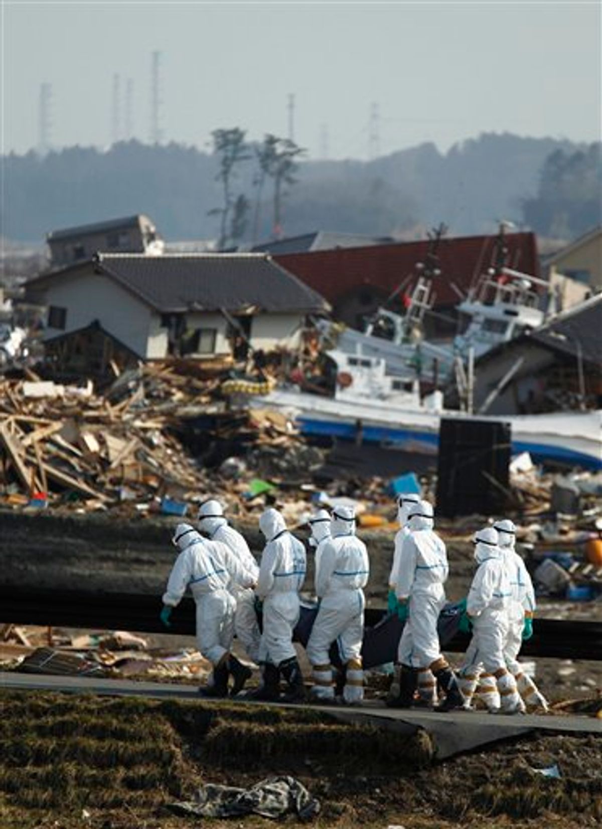 Japanese police officers carry a body during a search and recovery operation for missing victims in the area devastated by the March 11 earthquake and tsunami in Namie, Fukushima Prefecture, northeastern Japan, Friday, April 15, 2011. In the background is part of the Fukushima Dai-ichi nuclear complex.(AP Photo/Hiro Komae)  (AP)