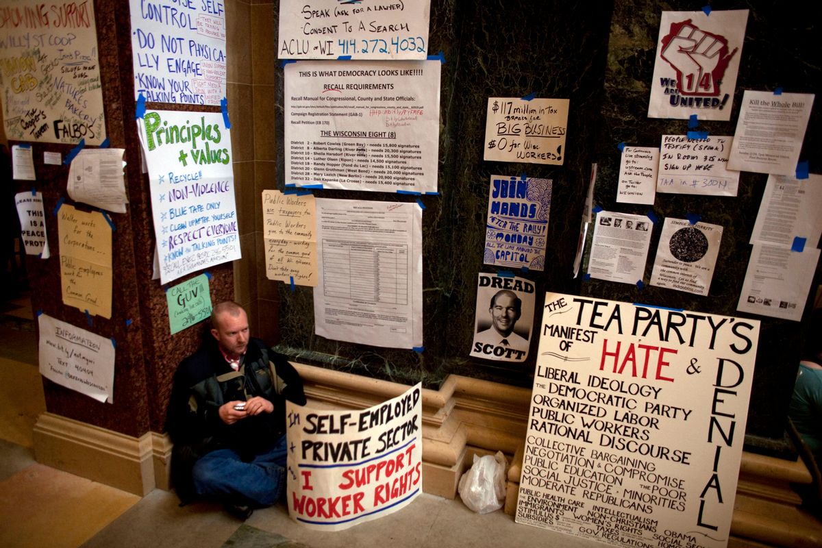 A man sits surrounded by protester signs on day eight of protests against the budget cuts proposed by Wisconsin Governor Scott Walker (Rep.) at the state Capitol in Madison, Wisconsin February 22, 2011. The Wisconsin state Assembly on Tuesday opened debate on a Republican proposal to curb the power of public sector unions that has sparked mass demonstrations and a tense stand-off with Democrats. REUTERS/Darren Hauck (UNITED STATES - Tags: POLITICS CIVIL UNREST) (Reuters)