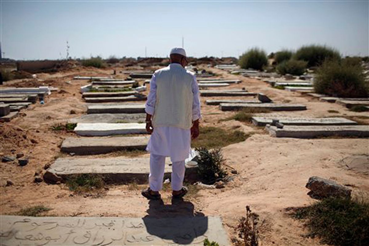 Mashud Marjub Orabi, retired oil company worker, stands next to the grave of his son and other rebel fighters, who he says were killed in Tripoli fighting against Moammar Gadhafi's troops, at a cemetery on the first day of Eid al-Fitr in Tripoli, Libya, Wednesday, Aug. 31, 2011. Muslims are celebrating the festival of Eid al-Fitr which marks the end of the holy fasting month of Ramadan. (AP Photo/Alexandre Meneghini) (Alexandre Meneghini)