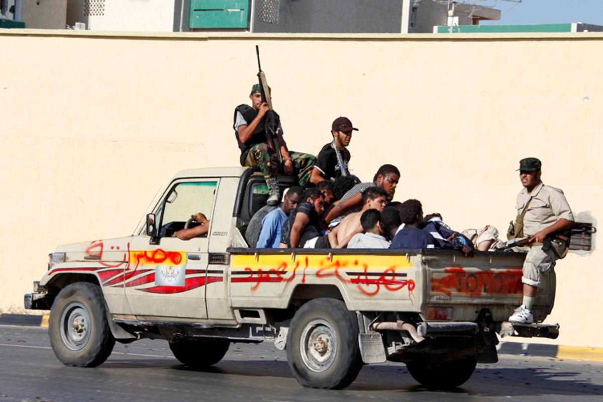 Libyan rebels secure prisoners in the back of a pick-up truck. The graffiti on the truck, in Arabic, reads, "Misrata steadfastness." (AP)