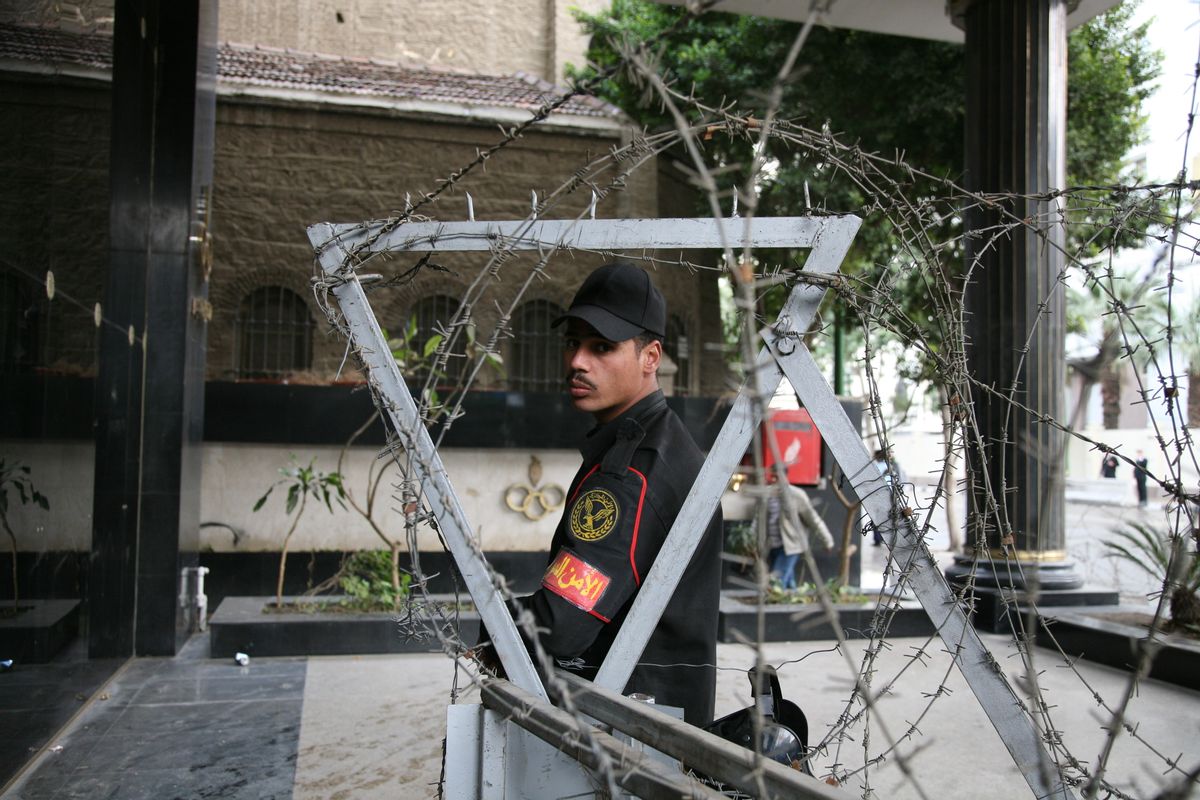  A guard stares through fencing and barbed wire in front of government offices in downtown Cairo, near Tahrir Square. Most of Cairo is untouched physically by the revolution, but a few areas remain specially guarded and prepared against riots. - [Michael Luongo/GlobalPost]                     